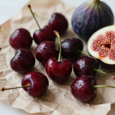 Intimate close-up of dark red cherries and fresh figs arranged on crumpled parchment paper, deep crimson tones, soft natural side-light