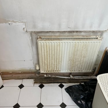 Rusty radiator that has been behind a radiator cover in a damp bathroom