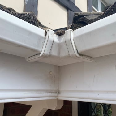 Gutter corner blocked with moss, overflowing down the wall