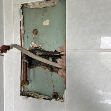 Leaking electric shower removed to expose the damage before repairing the wall and fitting a new one