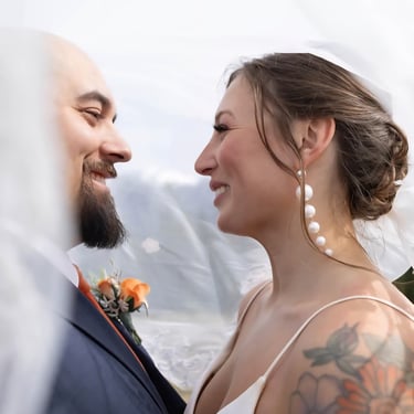a bride and groom standing in front of a veil