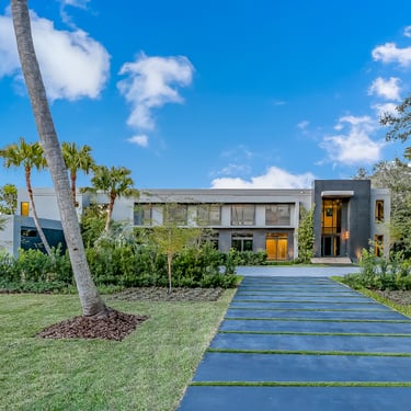 a long walkway to a huge luxury home with multiple garages