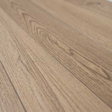 Low-angle macro shot of luxury vinyl plank showing realistic wood-look grain texture and heavy commercial wear layer