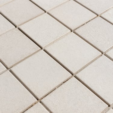 Close-up of clean grout lines and textured custom ceramic tiles laid in a precise herringbone pattern under bright daylight