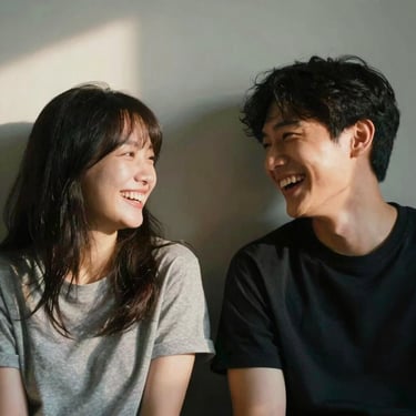Two people sharing a quiet, unposed laugh in a softly lit corner, gentle natural side-light highlighting their expressions.
