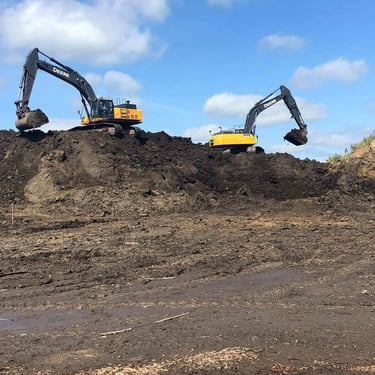 two excavators digging dirt on hill