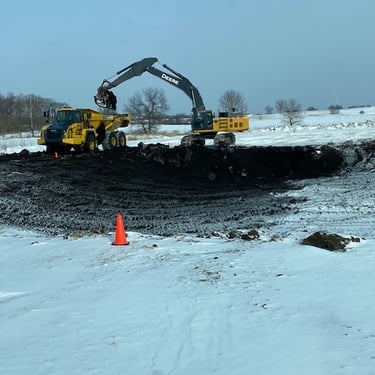 John Deere excavating pond in winter