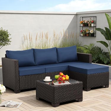 Modern outdoor sectional sofa with navy blue cushions and a matching wicker coffee table on a patio.
