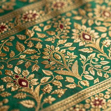 Macro shot of ornate gold brocade weave on emerald green textile, traditional Indian heritage pattern
