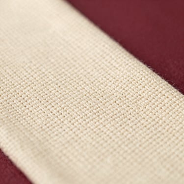 Macro close-up of textured cream cotton weave, warm directional light highlighting the fine thread count, tactile feel
