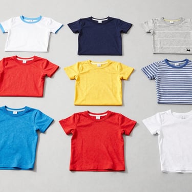 Clean flat-lay of children's colorful cotton tees and playwear on a light grey background, bright daylight