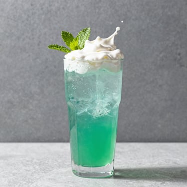 Vibrant green lime soda drink with a splash of sweet cream, fresh mint, bright event lighting