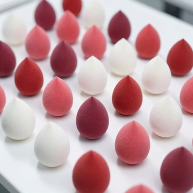 Multi-colored beauty blending sponges in a structured grid on a sterile white surface