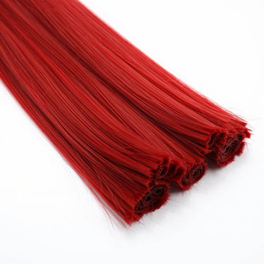 Straight raw human hair bundles stacked on a clean white factory table, bright high-key lighting