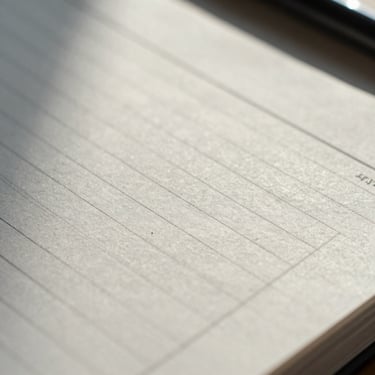 Macro close-up of a high-quality tactile paper ledger with clean ink lines under cool morning office light.