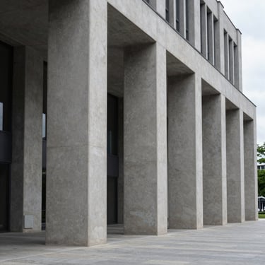 Wide-angle architectural detail of a modern civic financial institution with clean concrete pillars and sharp geometric shadows, cool overcast daylight.