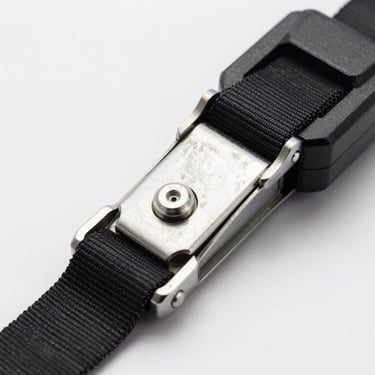 Close-up of an automatic self-retracting ratchet strap system on a clean white industrial background.