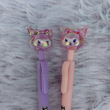 Close-up of cute purple and pink character-topped pens, a signature kawaii stationery find