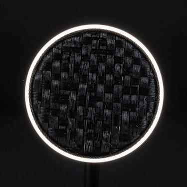 Macro close-up of raw black aramid fiber weave texture, high contrast rim lighting, deep black background