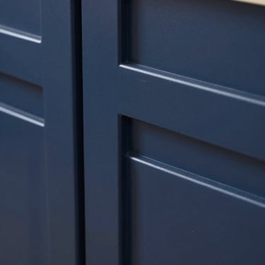 Macro detail of a double shaker cabinet door in deep navy blue, highlighting the dimensional depth and subtle inner step.
