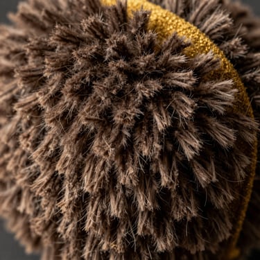 Extreme close-up of a fluffy chenille patch showing thick pile texture and gold felt backing.