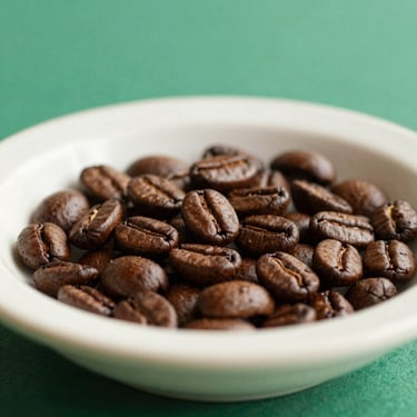 Close-up of roasted coffee beans in a clean ceramic dish, natural lighting