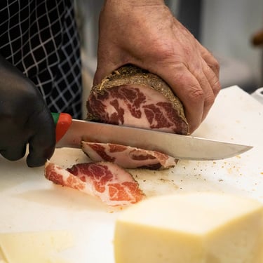 Taglio di salume su tagliere durante una degustazione