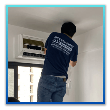 a JMLC Solutions technician in a blue uniform is installing an aircon