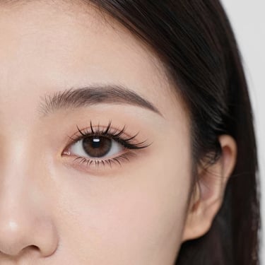 Close-up of a smiling woman showing off her perfectly lifted lashes in soft natural light.