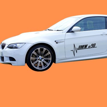 White BMW E90 M3 coupe with black heartbeat decal on orange background