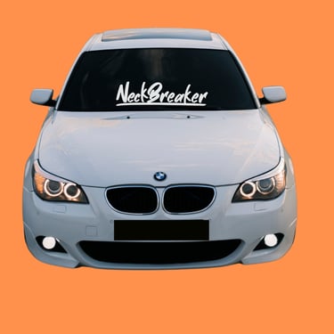 White BMW sedan with NeckBreaker windshield decal and halo headlights on an orange background.