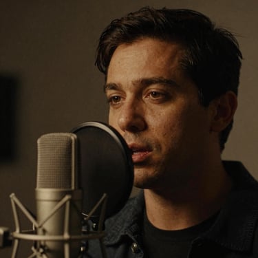 Intimate close-up portrait of a male voice actor speaking into a studio microphone, low-key lighting, warm amber glow, 35mm film grain, moody editorial style.