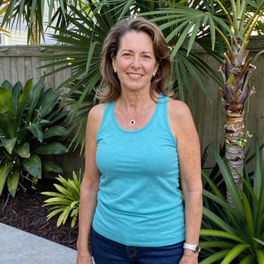 Smiling woman in her 50s enjoying a sunny morning outdoors with a fresh citrus drink.