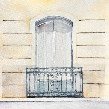 Arched window with wrought iron balcony railing on pale façade