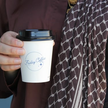 Guest holding hot latte in branded Friday Coffee Cart cup at Dallas even