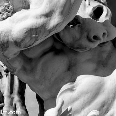 A black & white photo of a nude muscular male Roman style statue