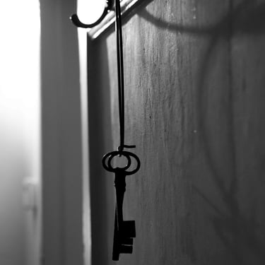 A black & white photo of two old skeleton keys hanging on a hook