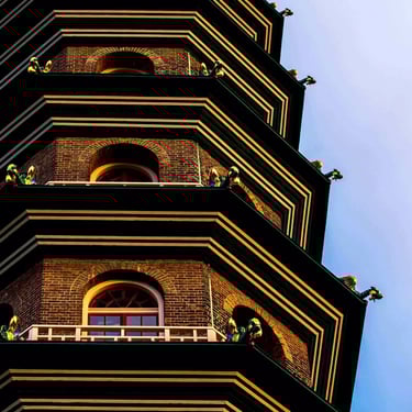 A close-up colour photograph of a Chinese pagoda with a dragon statue in each level’s corners. 