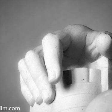 A black & white photo of a close-up on a sculpture of a man’s hand posed to rest
