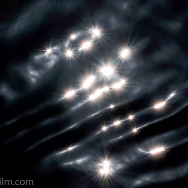 A photograph featuring rays of light reflecting on calm lake water.