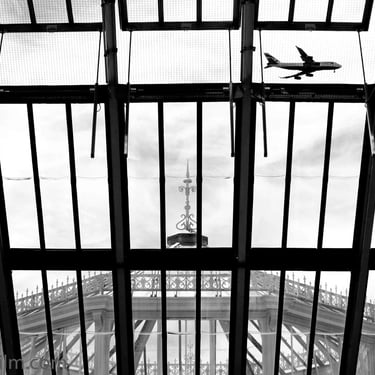 A black & white photo taken from below featuring an airplane seen through a glasshouse window