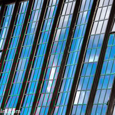 A colour photograph featuring old Elizabethan windows with the blue sky reflecting in them.