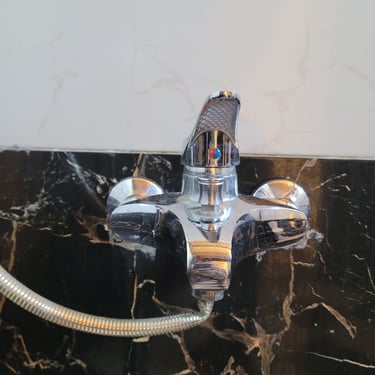 Mezclador de ducha cromado con indicadores de agua fría y caliente en un baño de estudio privado