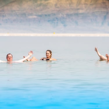 grupo de amigos dentro del agua del mar muerto en jordania durante un viaje organizado con Exclusive Jordan