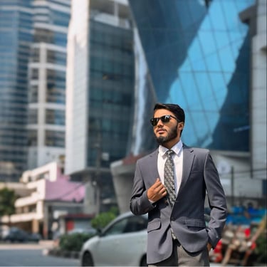 Professional businessman in a grey suit and sunglasses posing in a modern city business district.