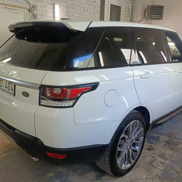 Balta „Range Rover Sport“ visureigė, stovinti garaže.