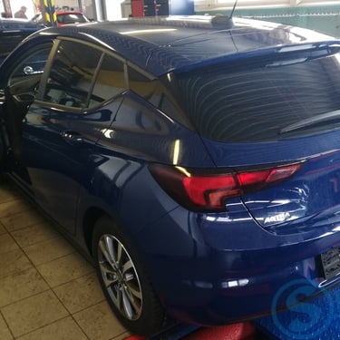 Mėlynas „Opel Astra“ hečbekas garaže su tamsintais stiklais.