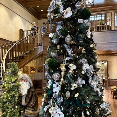 Large Christmas tree beside a staircase inside a Villages Ezell recreation center with elegant holiday decor