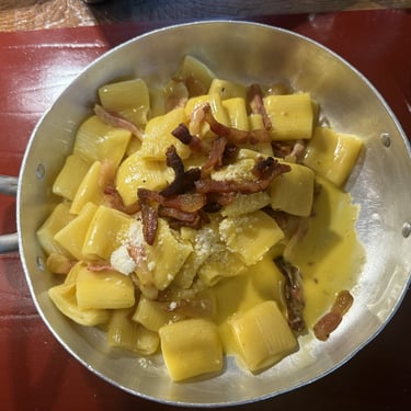 Carbonara pasta in a silver pan with pancetta with fork