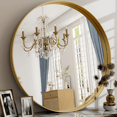 large round gold mirror reflecting gold chandalier in a room fill of large panel windows